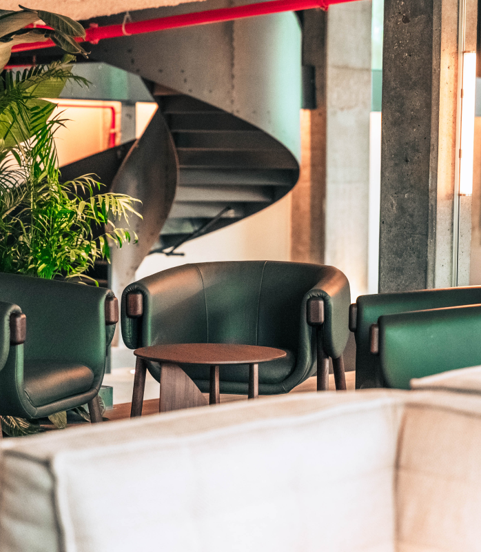 Foto van een high-end interieur van groene stoelen rond een bijzettafeltje met op de achtergrond een stijlvolle draaitrap